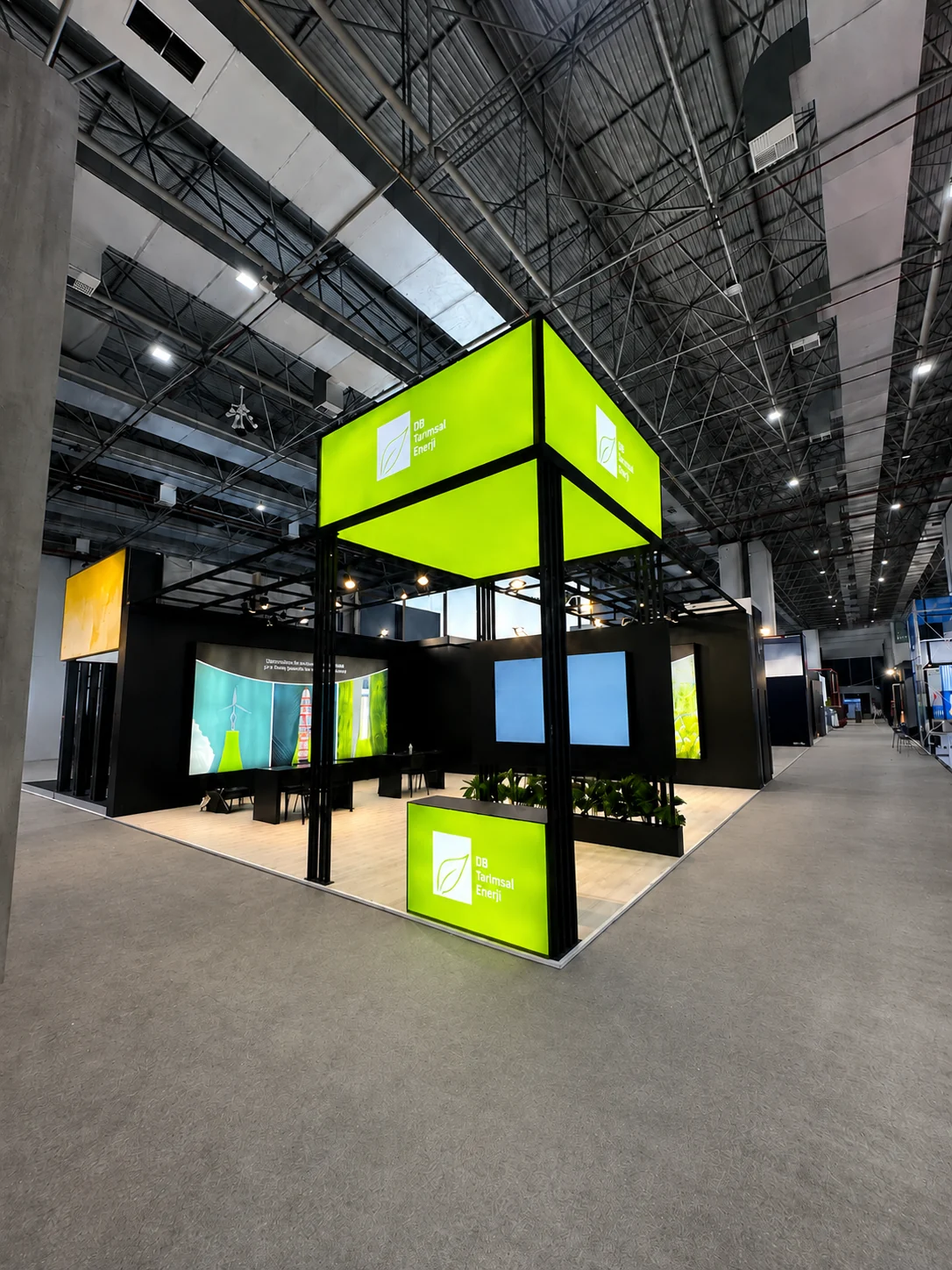 Corner view of the DB Tarımsal Enerji exhibition stand with illuminated green cube at Logistech İzmir 2025